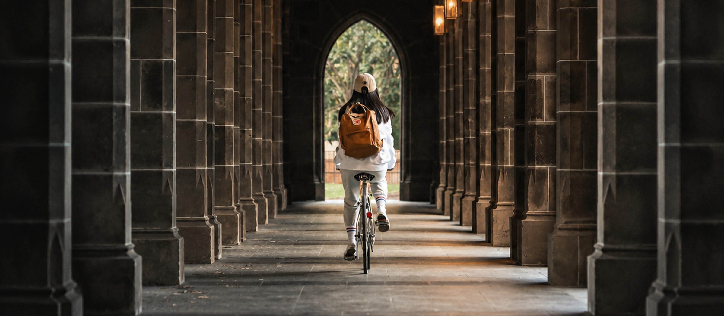 A cyclist moving through a dark arched corridor toward light.